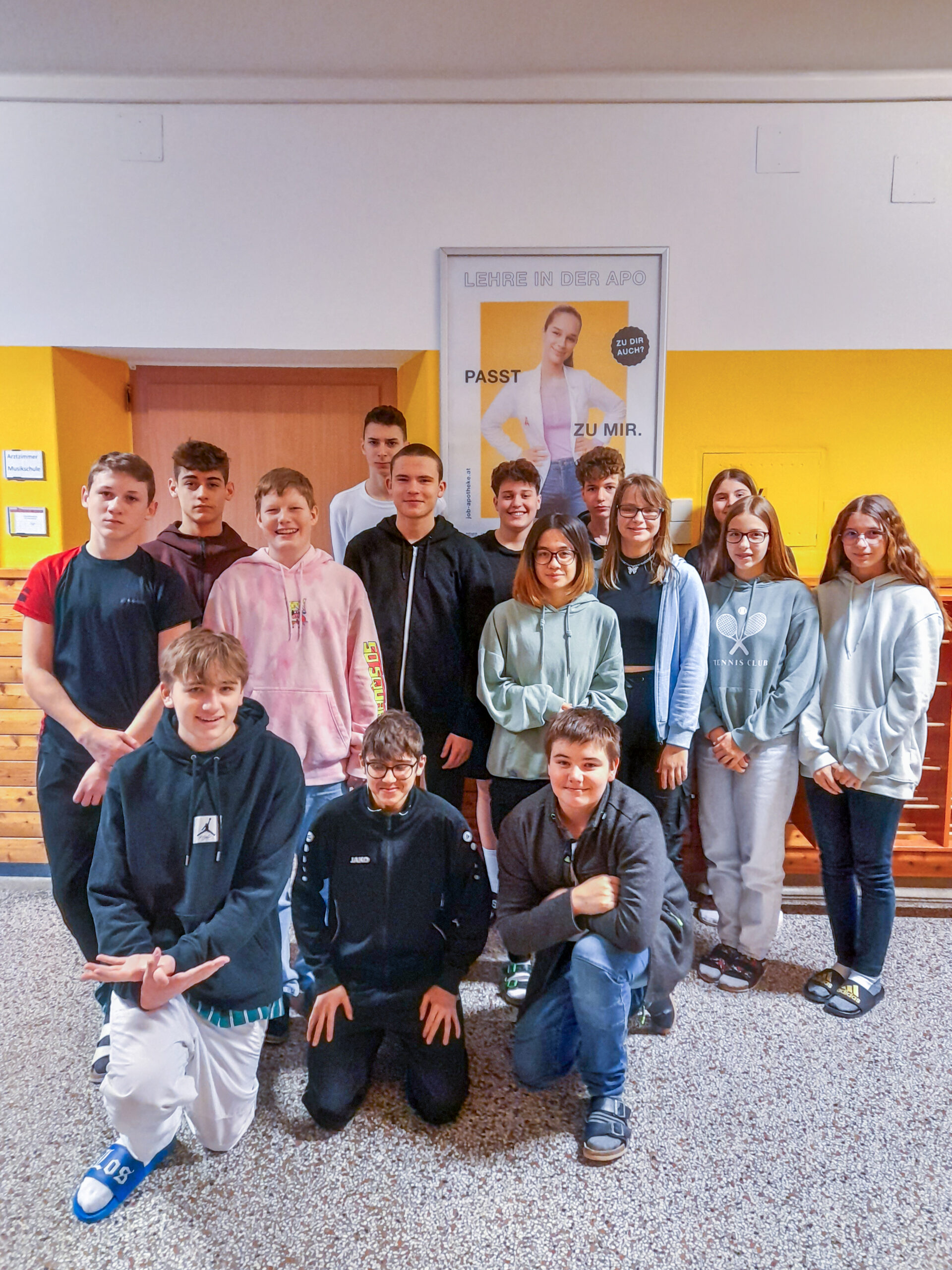 Schulklasse vor SChulplakat mit gelbem HIntergrund